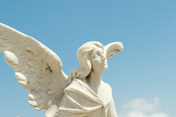 Statue de înger alb sub cer senin, simbol al protecției și ghidării divine în numerologia angelică